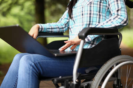 Woman in wheelchair on her knees with laptop