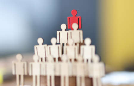 Pyramid of wooden figures of men at very top is only red figureの写真素材