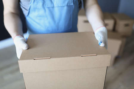 Man in uniform and gloves holding cardboard box closeupの写真素材