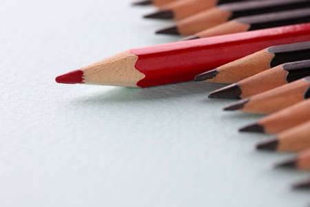 Red pencil lying among black on white background closeupの写真素材