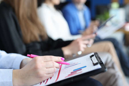 Woman analyzing graph on documents at business conference closeup