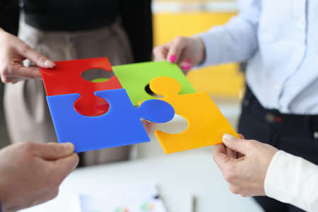 Business people putting together colorful puzzle closeup