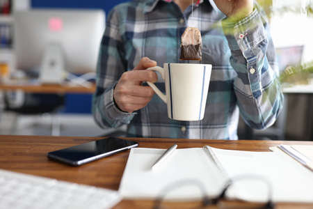 Woman putting tea bag into cup at table closeupの写真素材