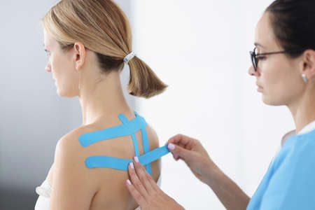 Doctor gluing blue tape on patient back closeupの写真素材