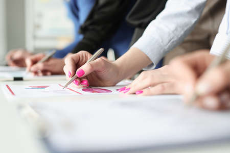 Hands of employees with pens and business graphs with financial indicatorsの写真素材