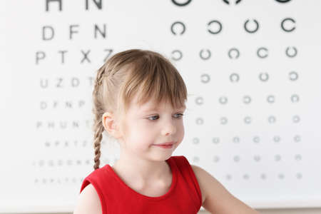 Little girl sitting near table for eye examinationの写真素材