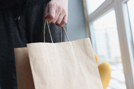Woman hand holding paper bag at home closeupの写真素材