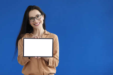 Woman with glasses holding digital tablet with white screen in her handsの写真素材