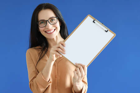 Woman with glasses holding blank sheet of paper in her handsの写真素材