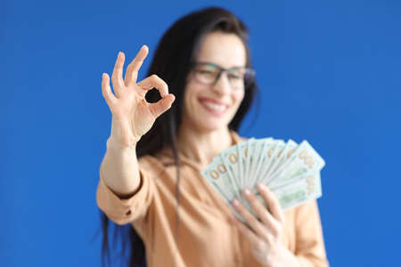 Woman holding dollar bills in her hands and showing ok gesture closeupの写真素材