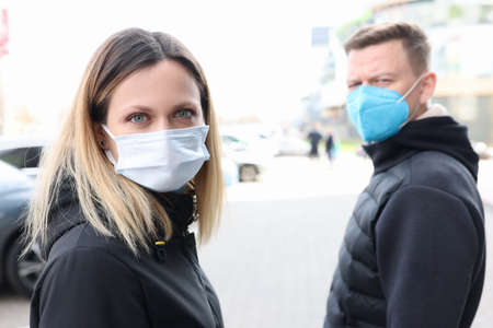 Young man and woman walking down street wearing protective masks