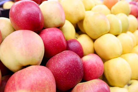 Many yellow and red apples lying on counter of store closeupの写真素材