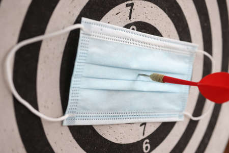 On playing darts, protective medical mask with dart in center