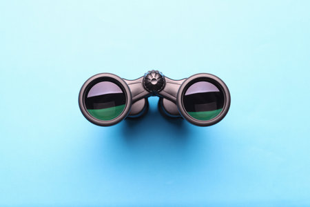 Black professional binoculars lying on blue backgroundの写真素材