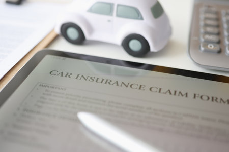 Digital tablet with car insurance form lying on table near toy car closeupの写真素材
