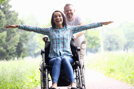 Guy carries joyful woman in wheelchair closeupの写真素材