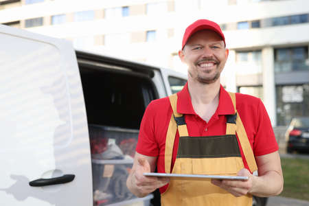 Man courier in uniform holding digital tablet near carの写真素材
