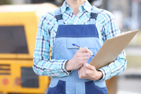Woman builder in overalls holding clipboard and ballpoint pen closeupの写真素材