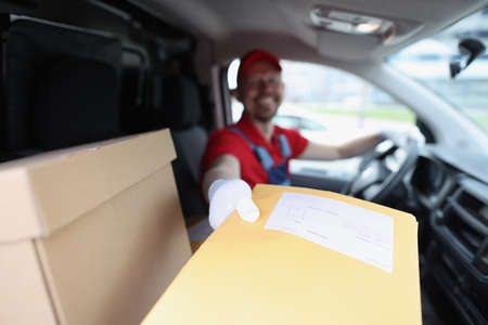 Man delivering yellow envelope from car closeupの写真素材