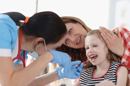 Doctor taking buccal dna swab from little girl in clinicの写真素材