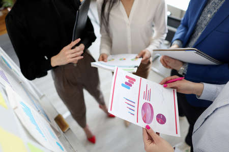 Group of people with documents in hands standing near blackboard at business training closeupの写真素材