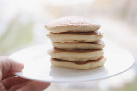 Stack of delicious pancakes lie on white plate