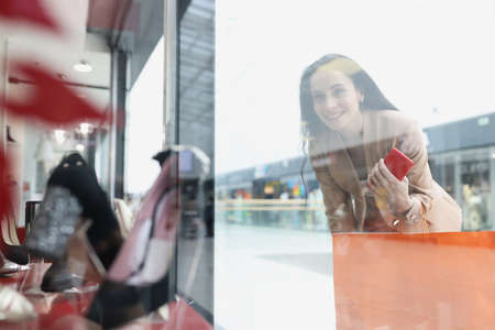 Smiling woman looks at shop window with women shoes