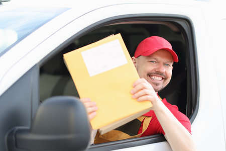 Smiling male courier driver holds mail in his handsの写真素材