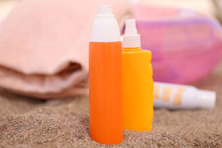 Lotion and sunscreen stand on sand on beachの写真素材