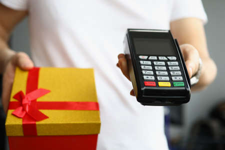 Payment by credit plastic bank card at terminal to courier with gift boxの写真素材