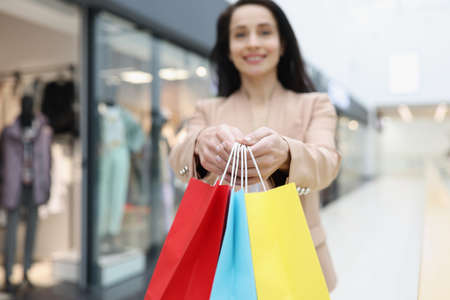 Woman holding in hands many multicolored paper bags with purchases in store closeupの写真素材