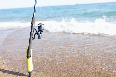 Fishing rod for catching fish stands on coastline of seaの写真素材