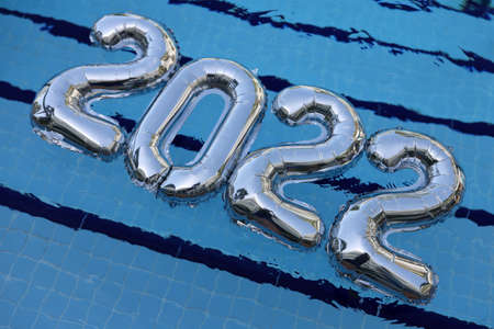 Inflatable numbers 2022 lie on clear blue water of pool