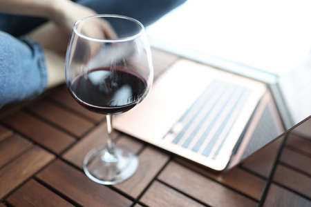 Glass of red wine stands on floor next to man sits in backgroundの写真素材
