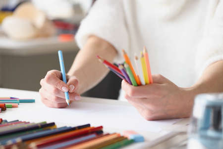 Woman drawing with multicolored pencils on white sheet of paper closeupの写真素材