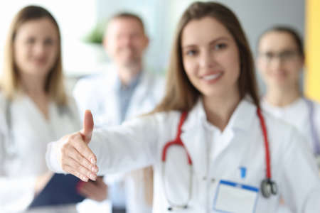 Woman doctor giving hand for handshake on background of colleagues in clinic closeupの写真素材