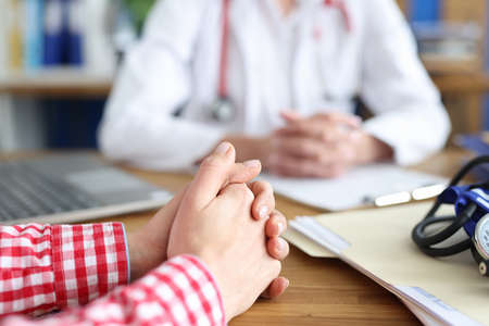 Woman sitting at table at doctor appointment in clinic closeup