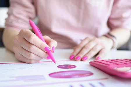 female analyst examines business report in form of graphsの写真素材