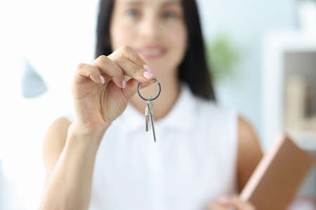 Smiling woman holds in hand keys to housingの写真素材