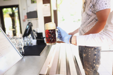 Hand in glove in front of cold glass with kvass or beer