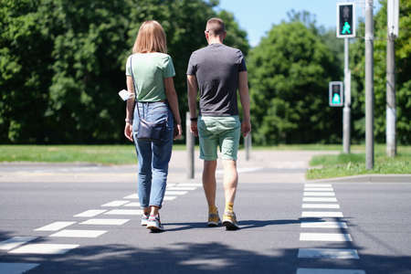 Man and woman cross the road at pedestrian crossing