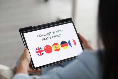 Woman holds tablet and chooses a foreign language to studyの素材 [FY310171426132]