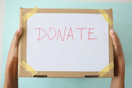 Female hands holding cardboard box with inscription donate closeupの写真素材