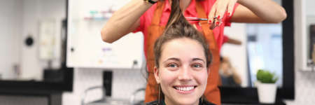 Portrait of smiling woman in hairdressing salon, which master cuts her hairの写真素材