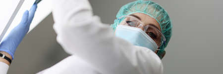 Medic is holding an X-ray in medical protective mask
