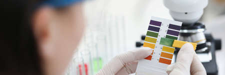 Researcher holds Ph test strip for research.の写真素材