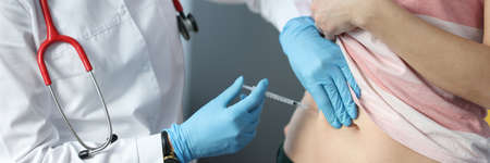 Doctor making injection of insulin into abdomen of female patientの写真素材