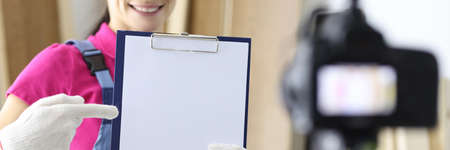 Woman builder holding documents in hands and shooting video on cameraの写真素材