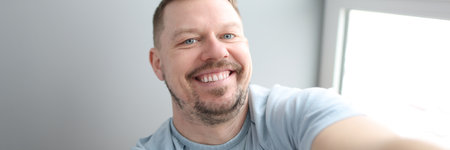 Young smiling man taking selfie at home