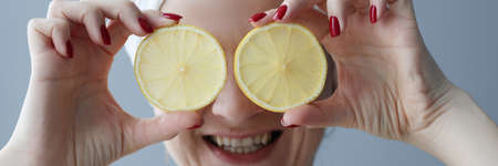 Young woman holding lemons in front of her eyesの写真素材